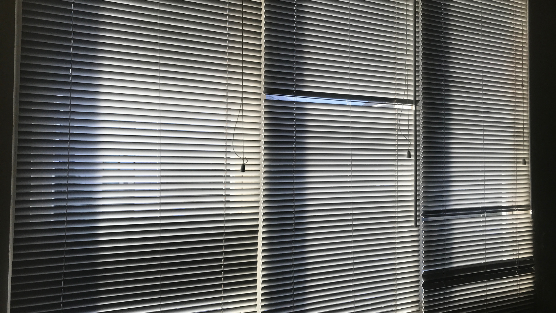 A black and white photo of a window with blinds on it.