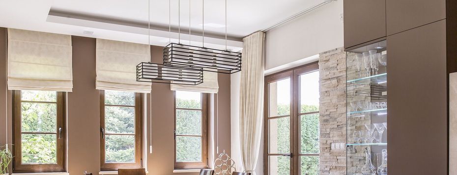 A dining room with a lot of windows and a chandelier hanging from the ceiling.