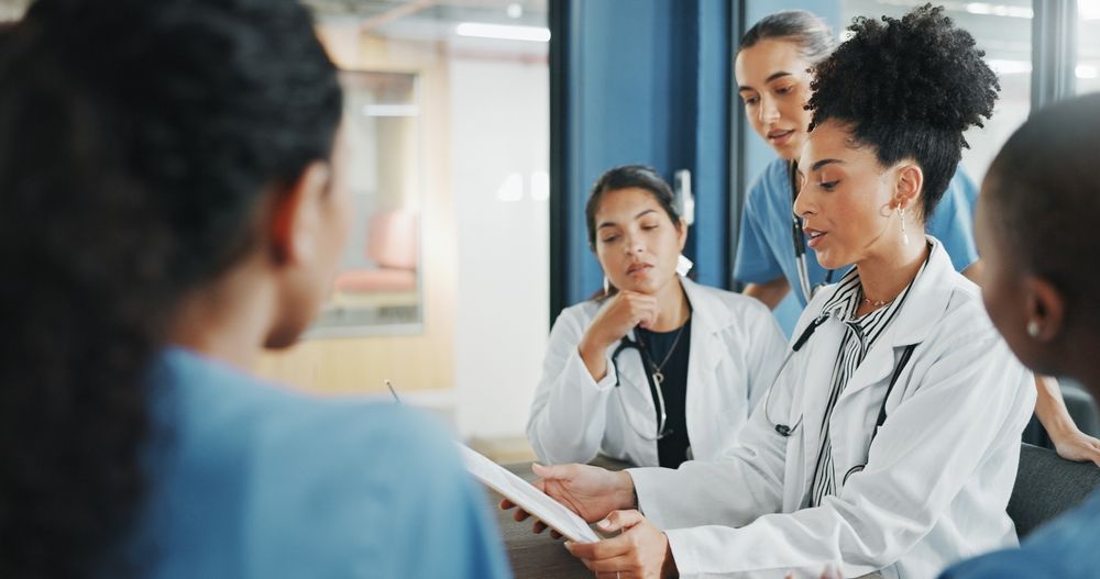 Healthcare team discussing patient care in a bright hospital meeting room, one doctor holding papers