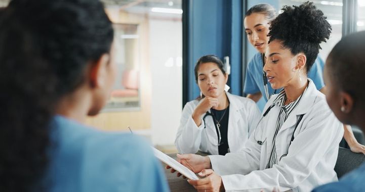 Healthcare team discussing patient care in a bright hospital meeting room, one doctor holding papers