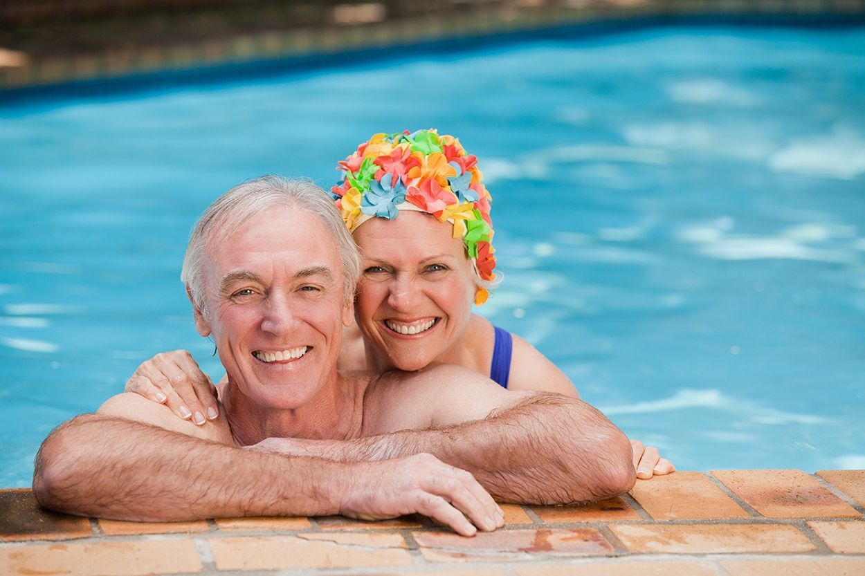 a man and woman are posing for a picture in a swimming pool