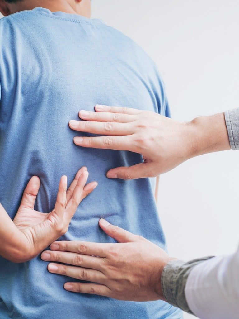 a man in a blue shirt is having his back examined by a doctor