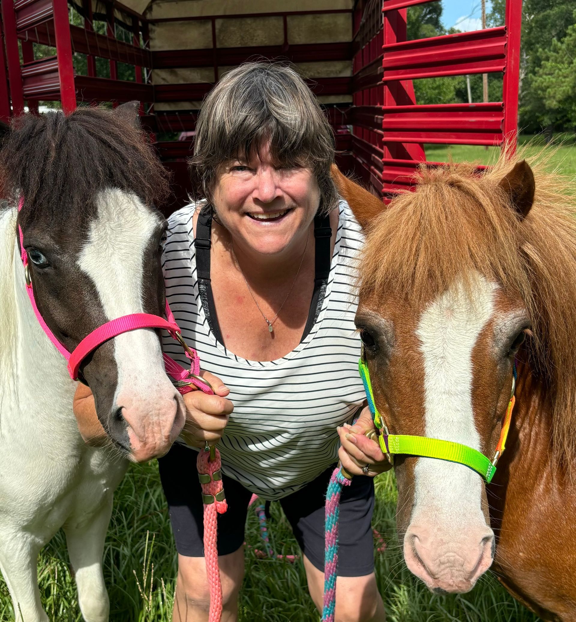 A woman is posing for a picture with two horses.