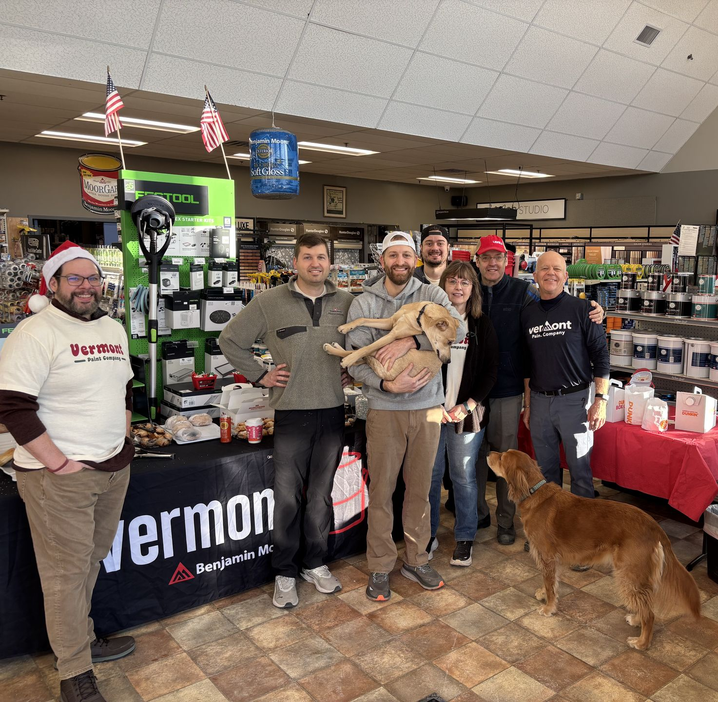 Group of people and dogs by a Christmas tree inside a store.