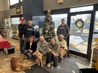 Group of people and dogs by a Christmas tree inside a store.