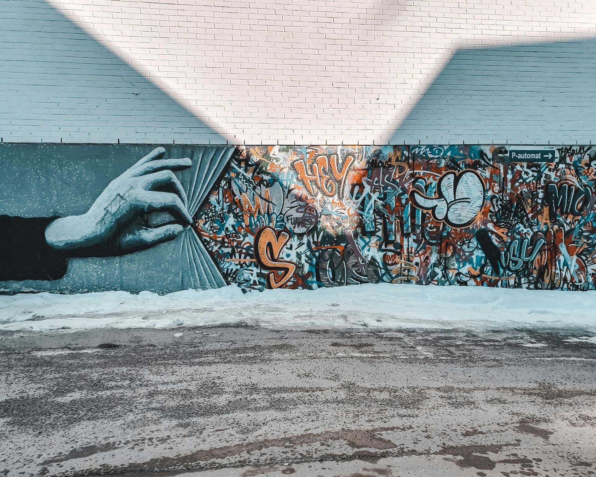 A mural of a hand holding a book on a brick wall.