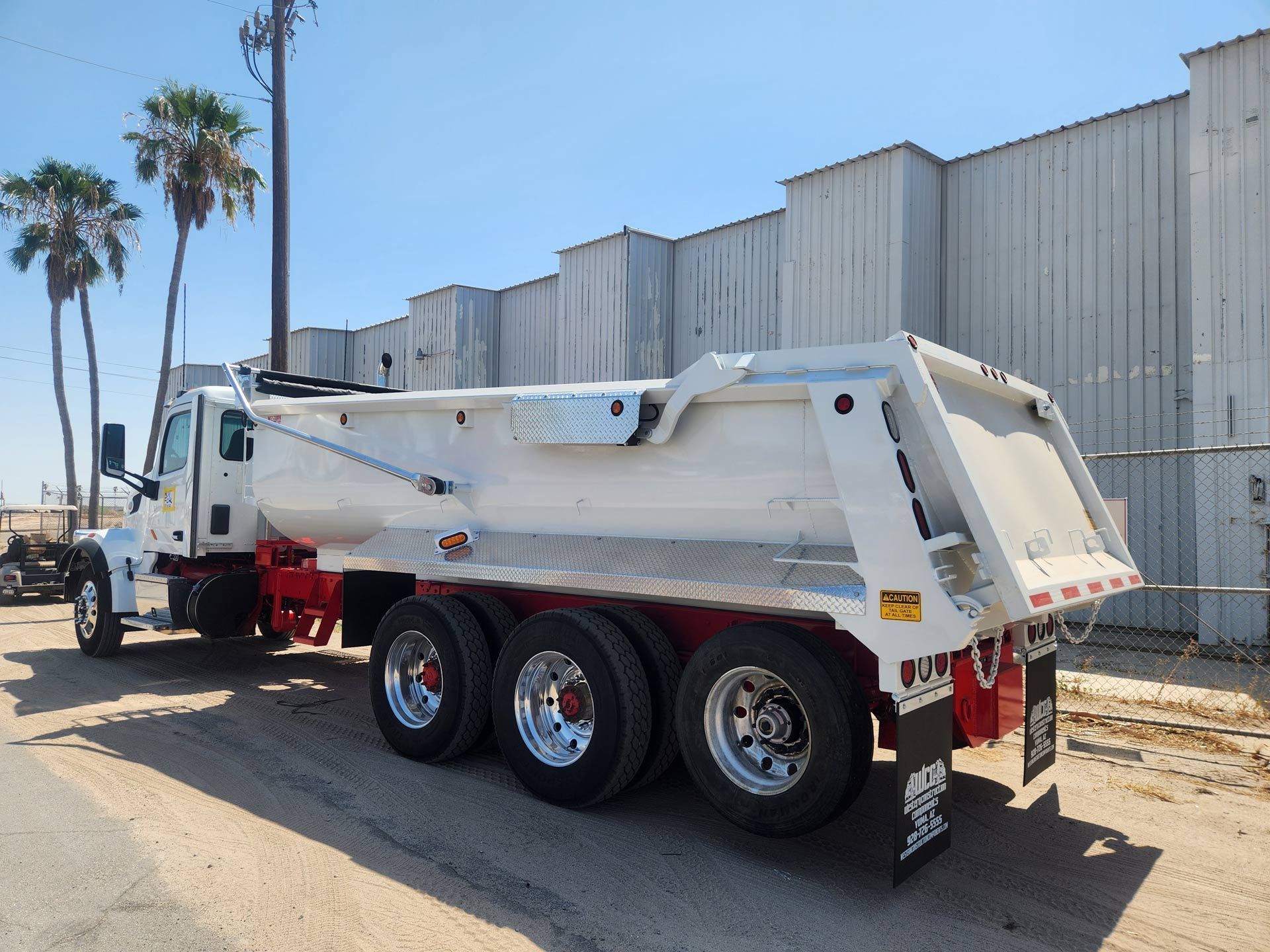 A white dump truck is parked in front of a building