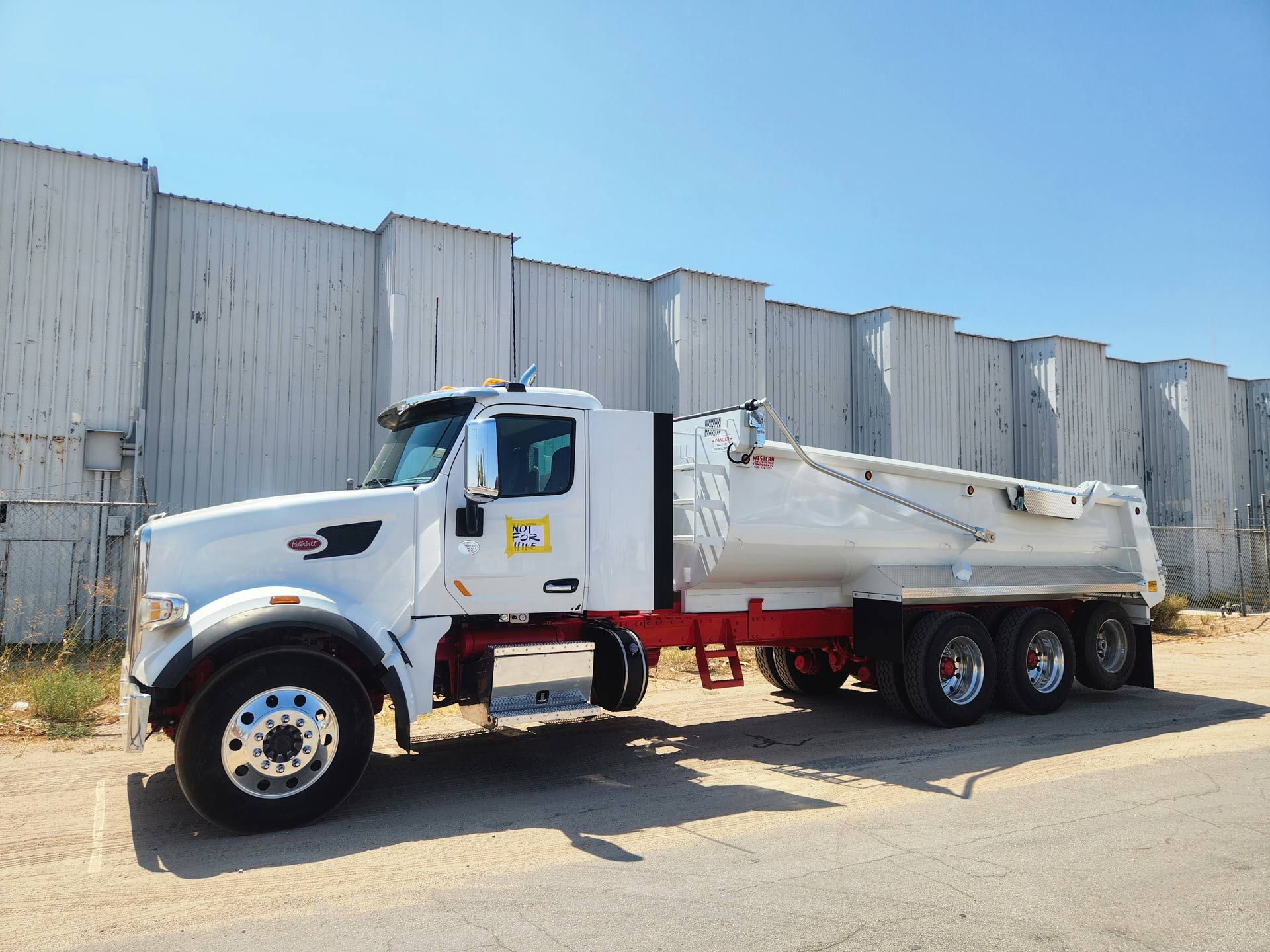 A white dump truck is parked in front of a building.