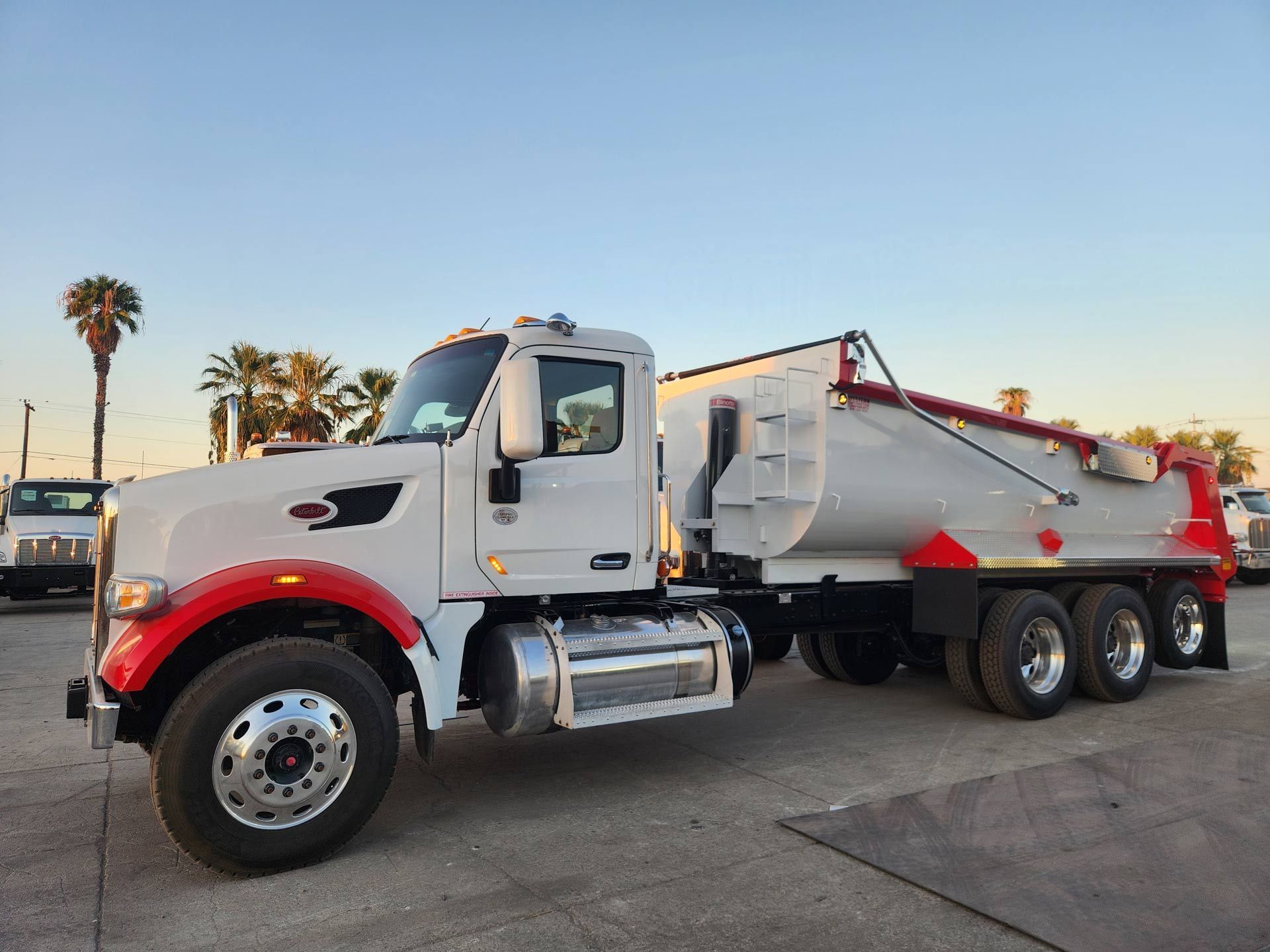 A white and red dump truck is parked in a parking lot.