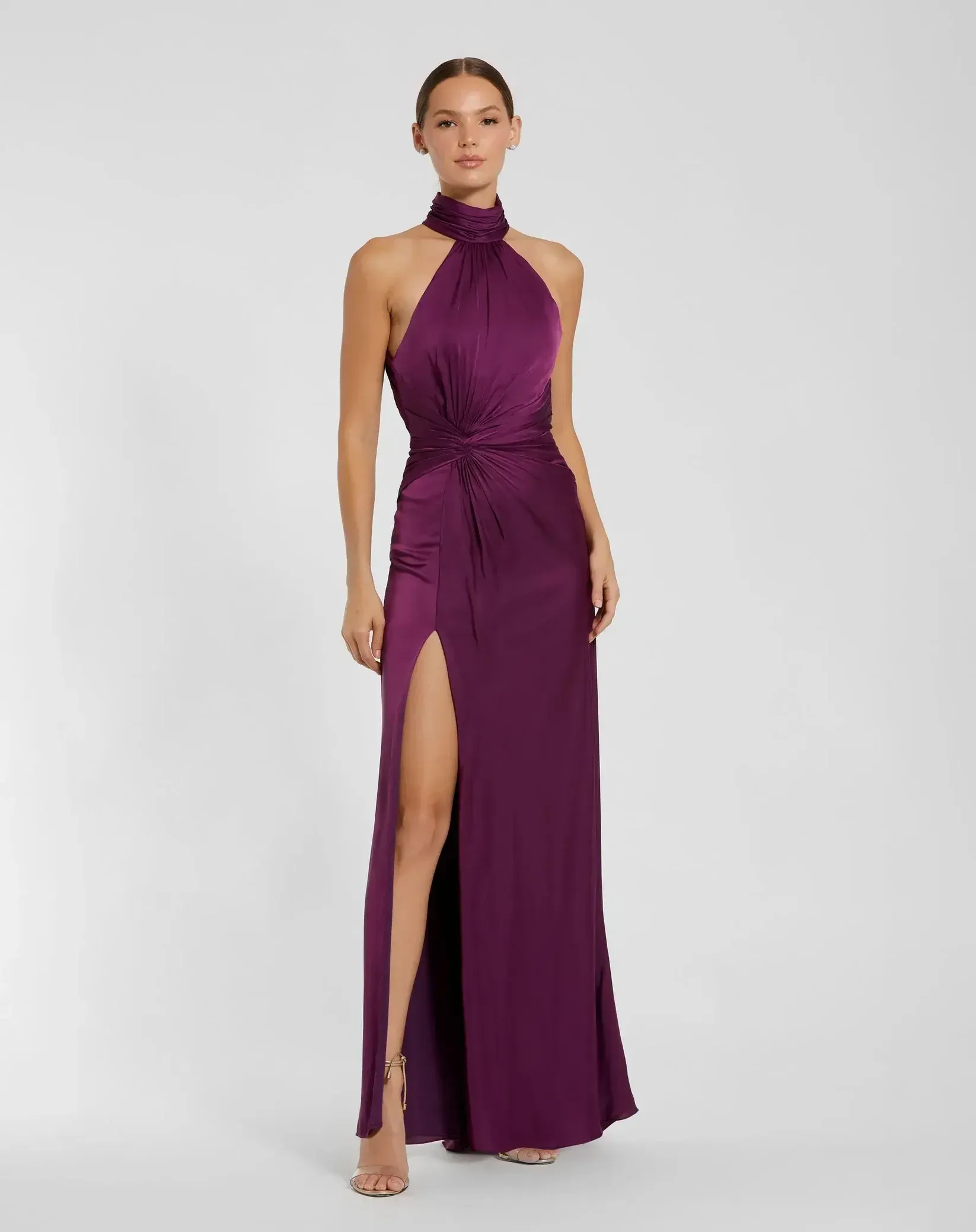 A woman is wearing a purple halter dress with a high slit.