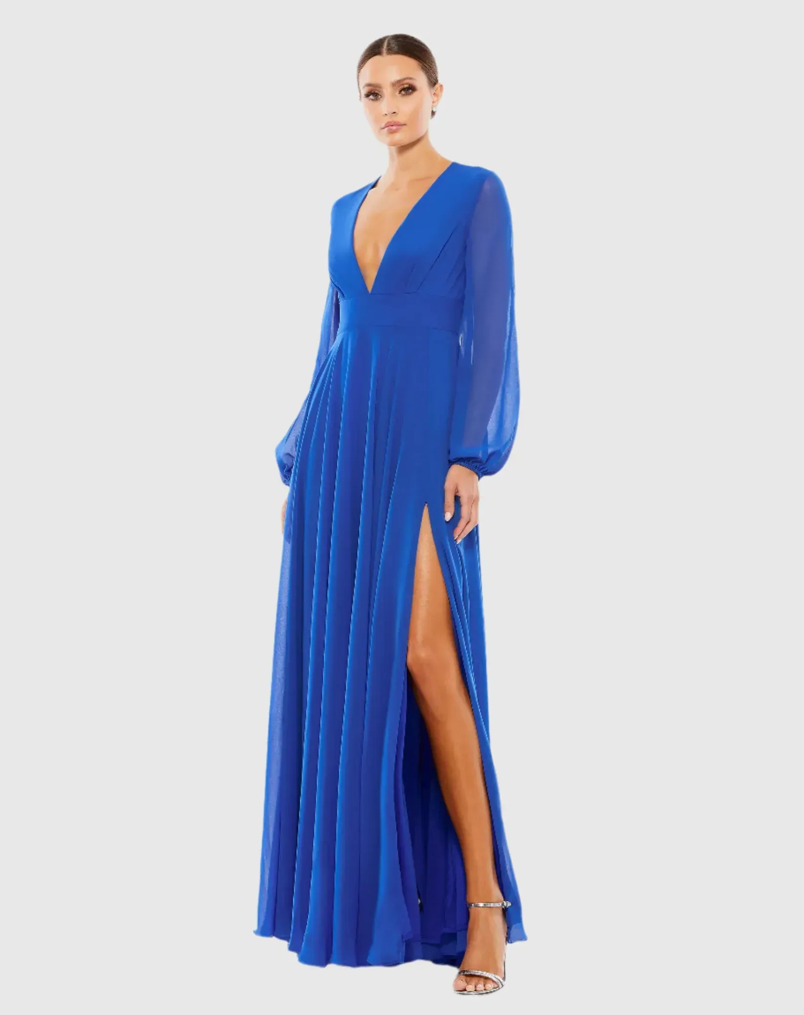 A woman is wearing a long blue dress with a high slit.