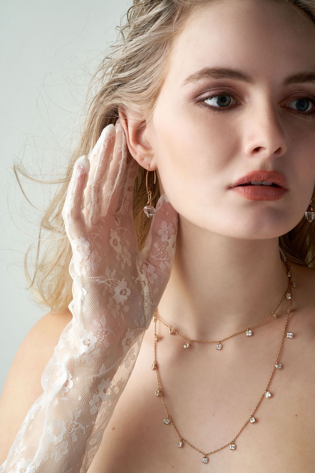 A woman wearing white lace gloves and a necklace.