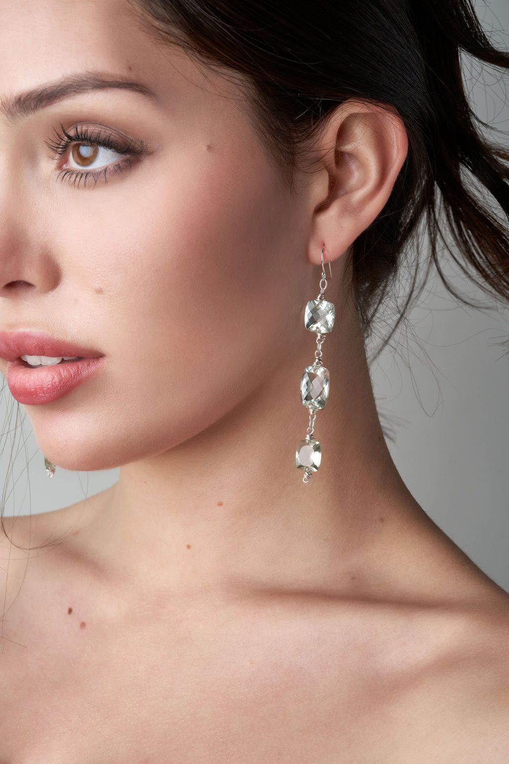 A close up of a woman wearing a pair of long earrings.