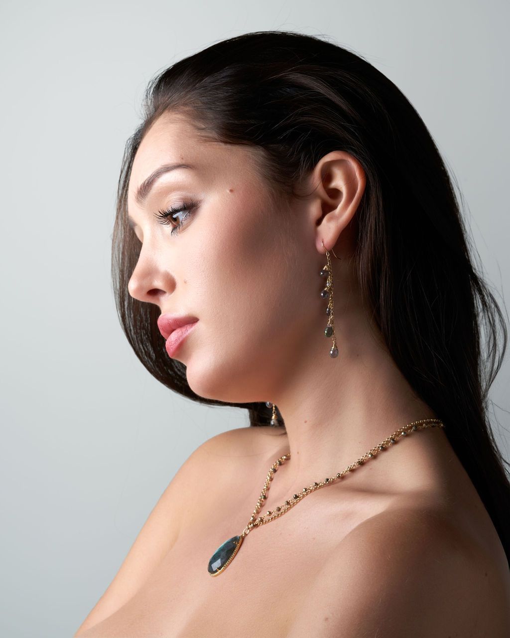 A woman wearing a necklace and earrings looks to the side