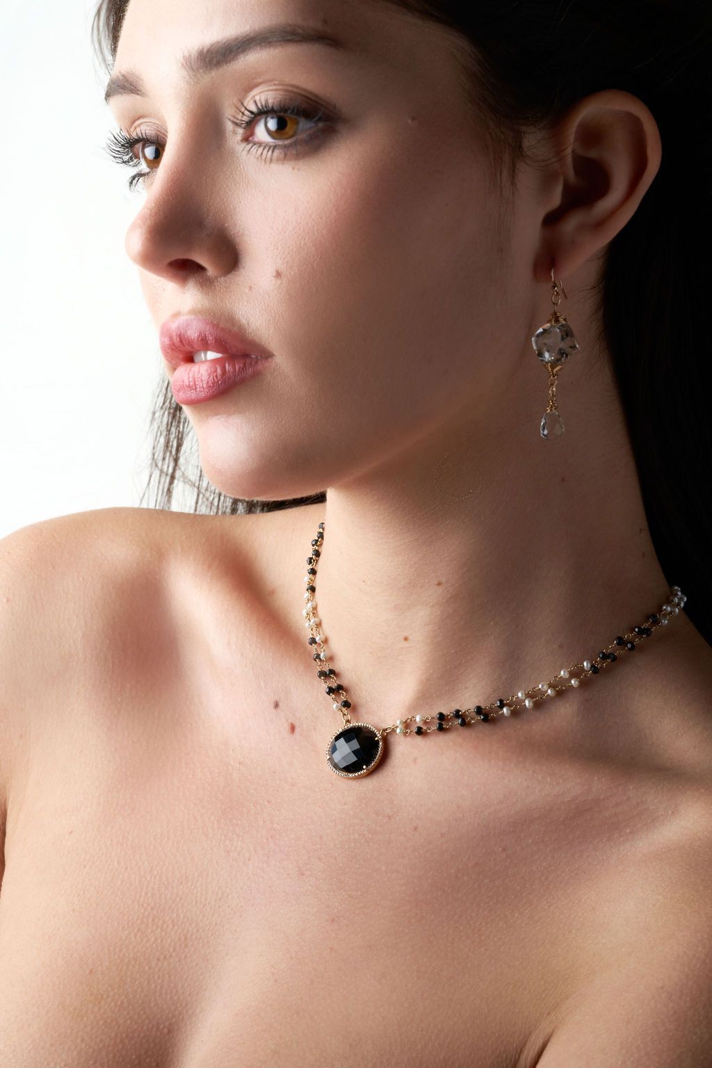 A woman is wearing a necklace and earrings.