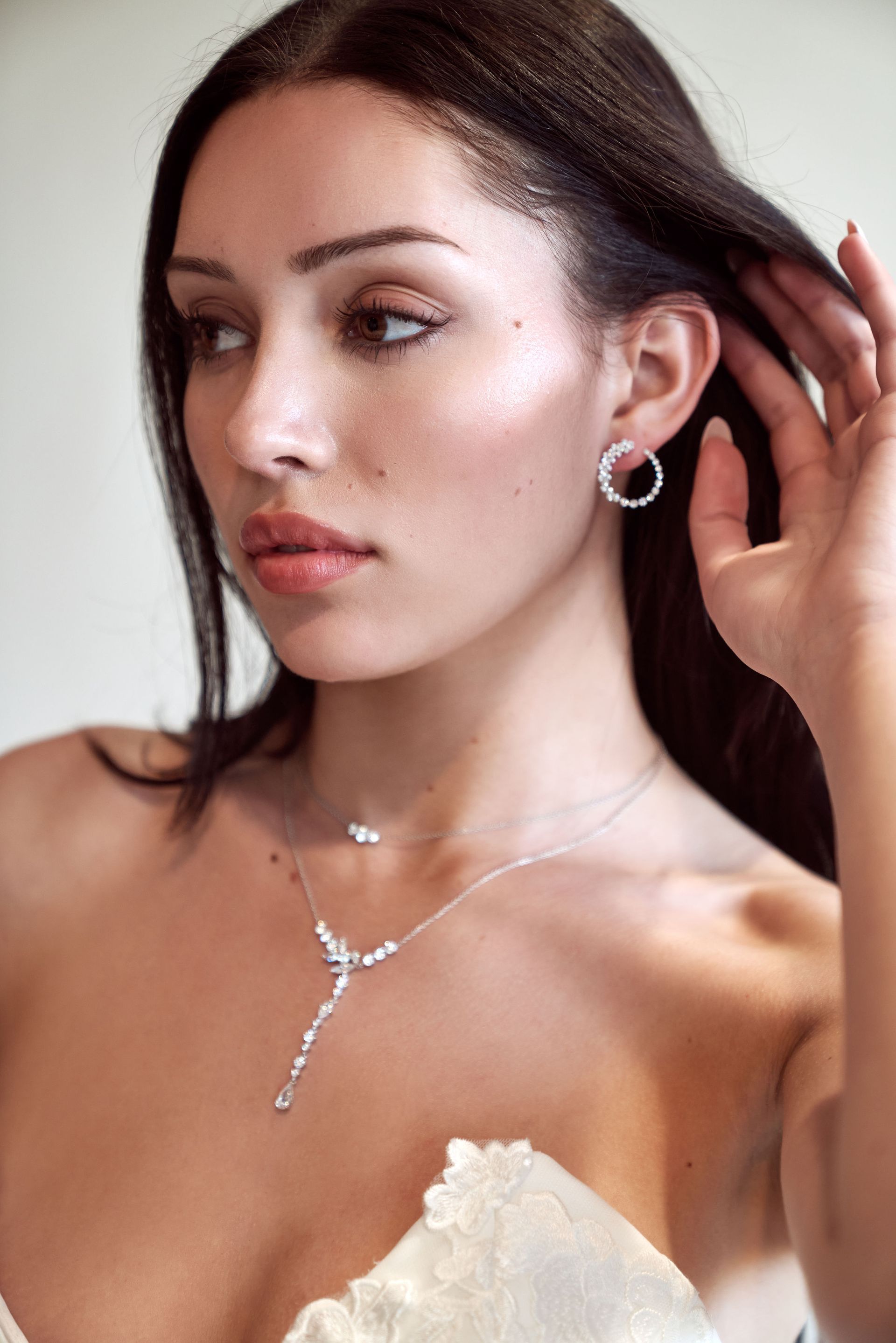 A close up of a woman wearing a necklace and earrings.