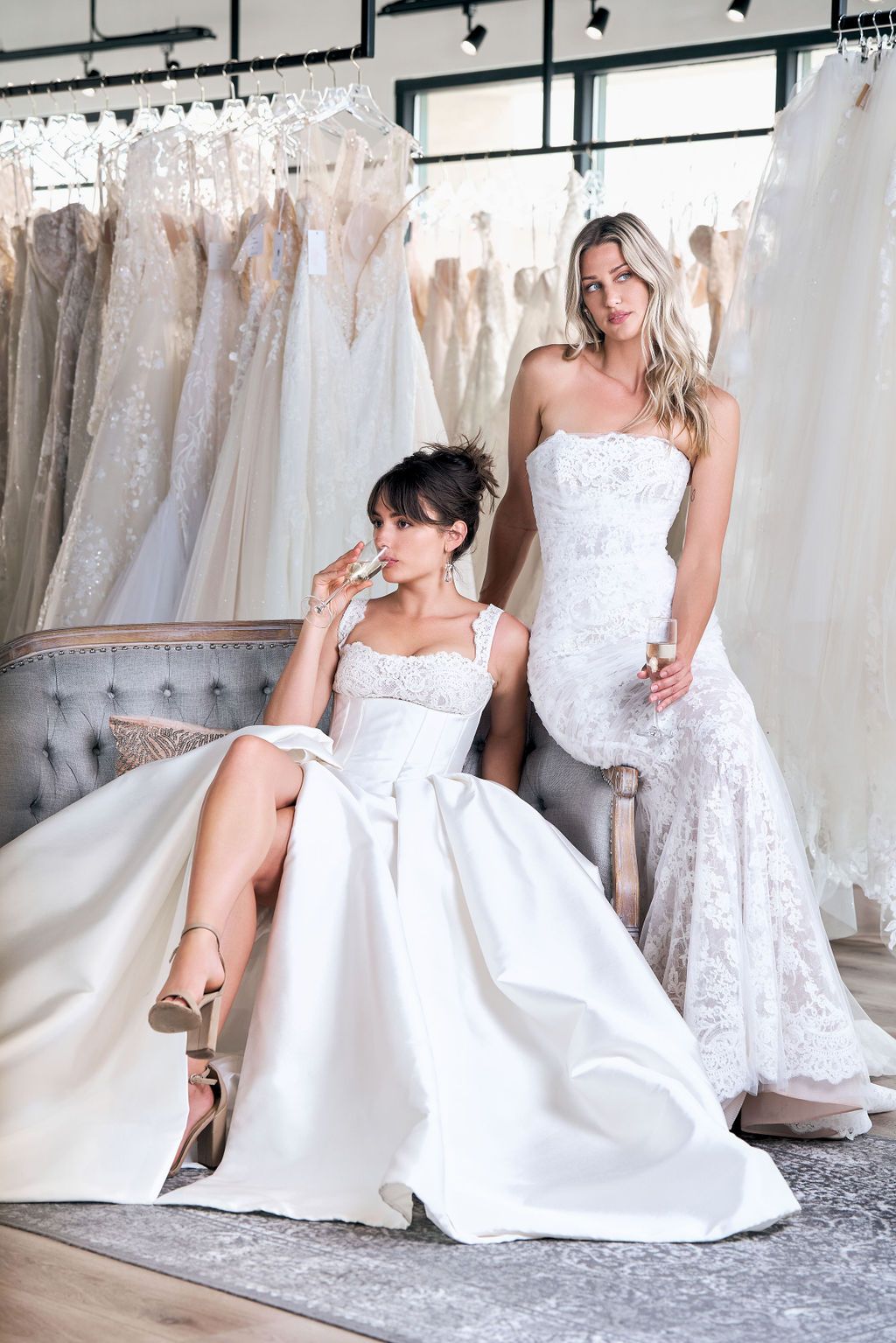 Two women in wedding dresses are posing for a picture in a bridal shop.