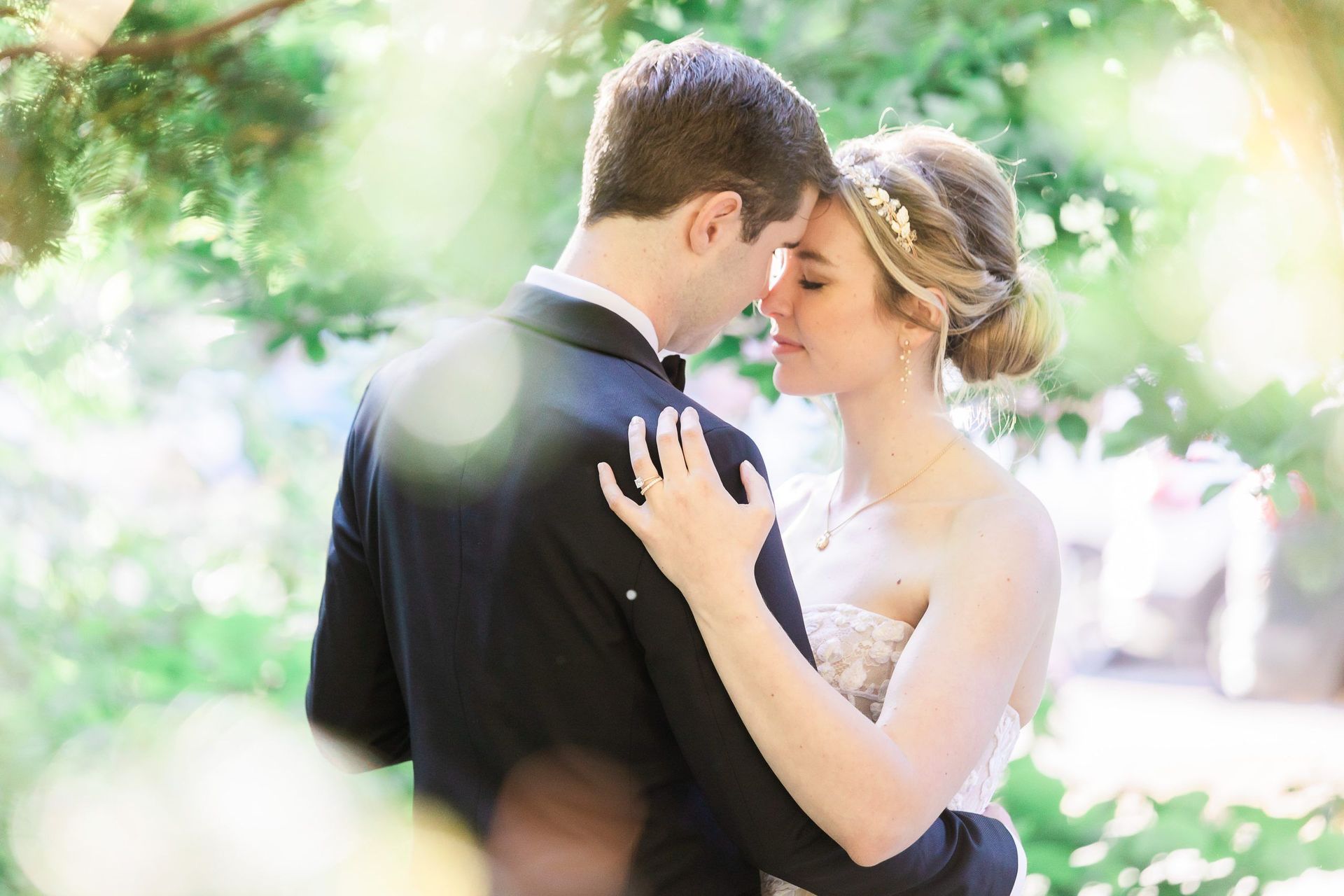 A bride and groom are standing next to each other and touching their foreheads.
