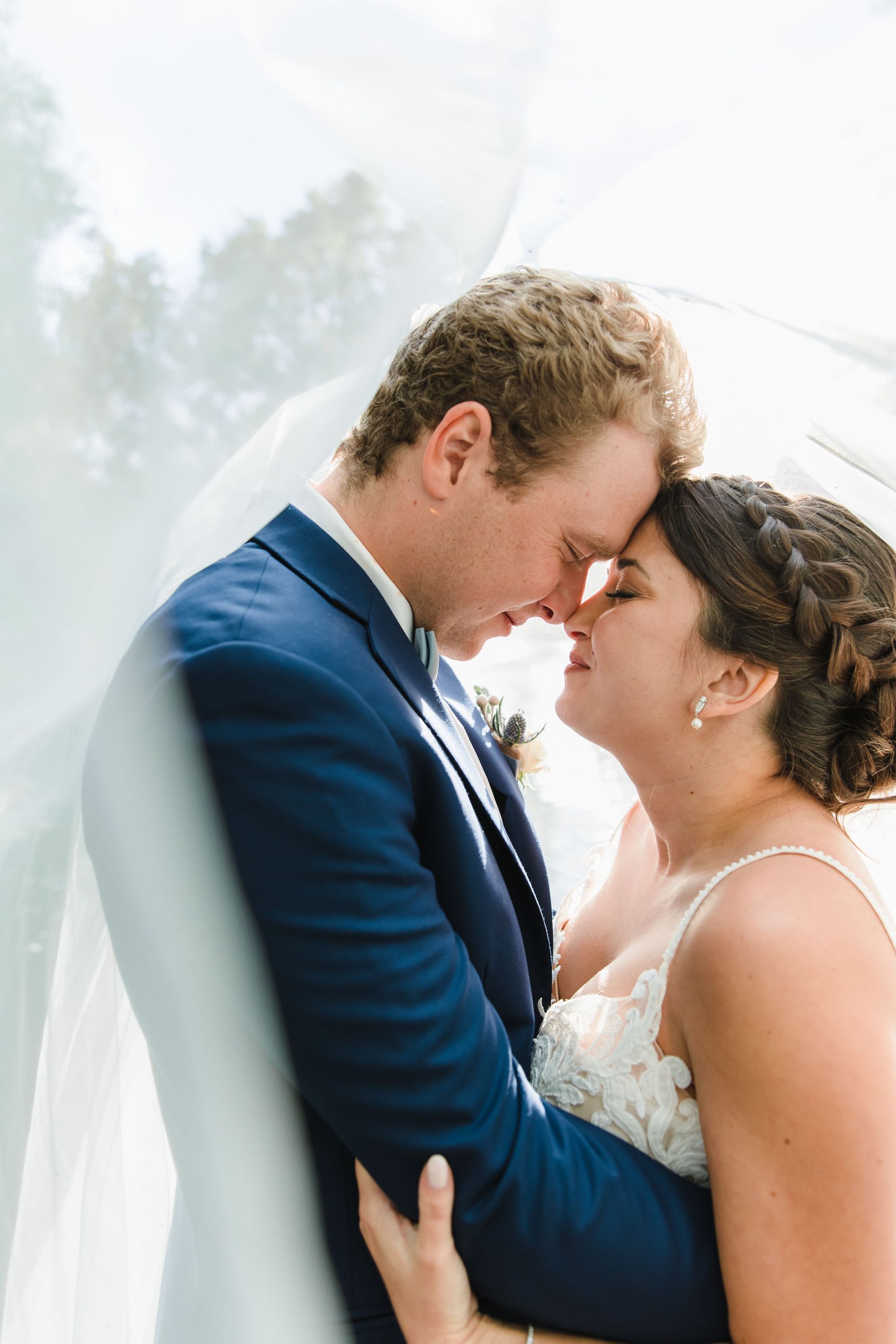 A bride and groom are kissing under a veil.