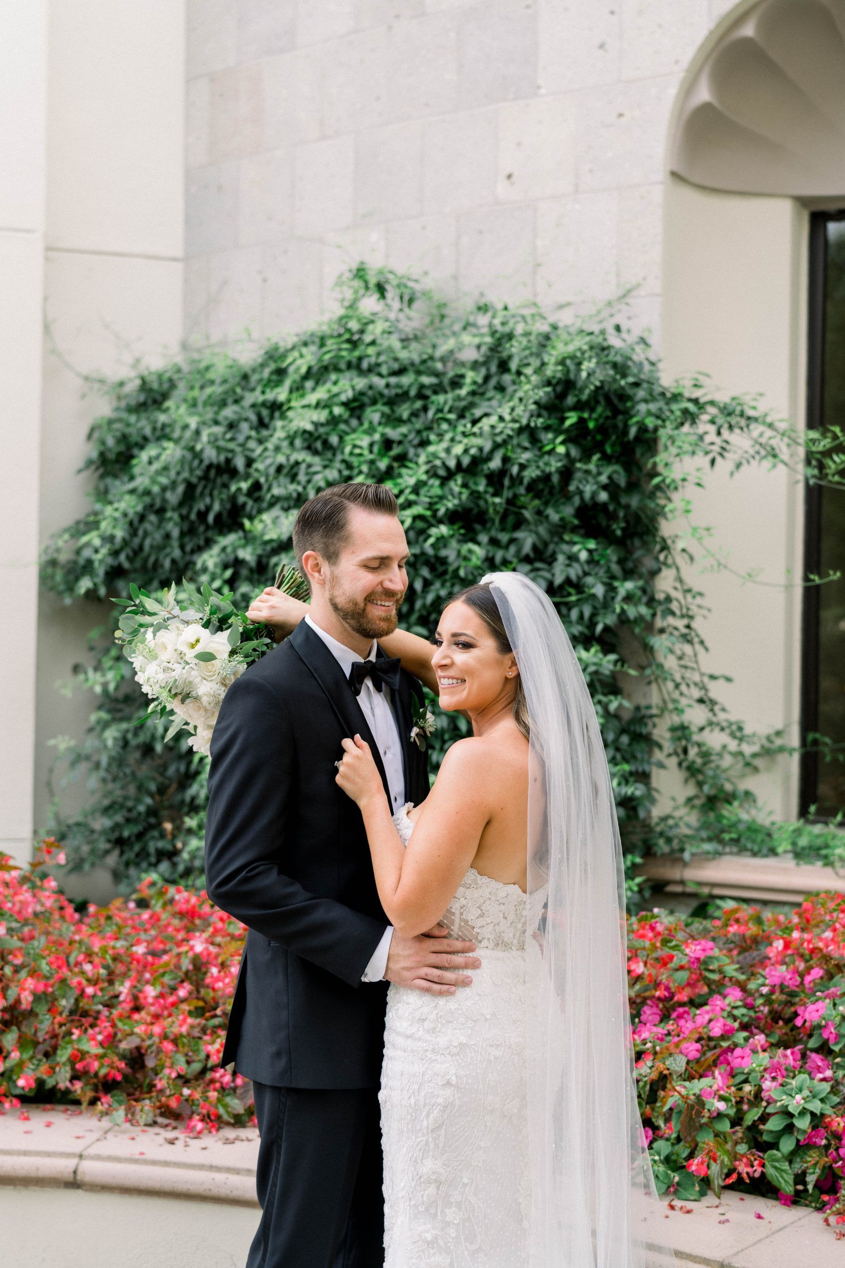 A bride and groom are posing for a picture in front of a building.