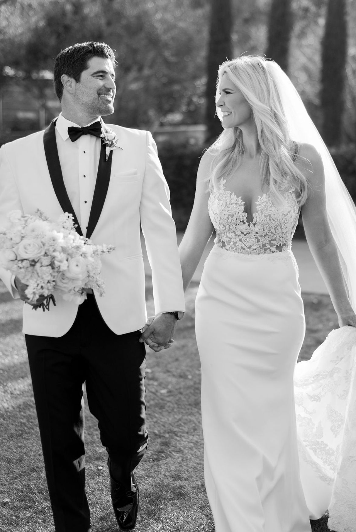 A black and white photo of a bride and groom holding hands.