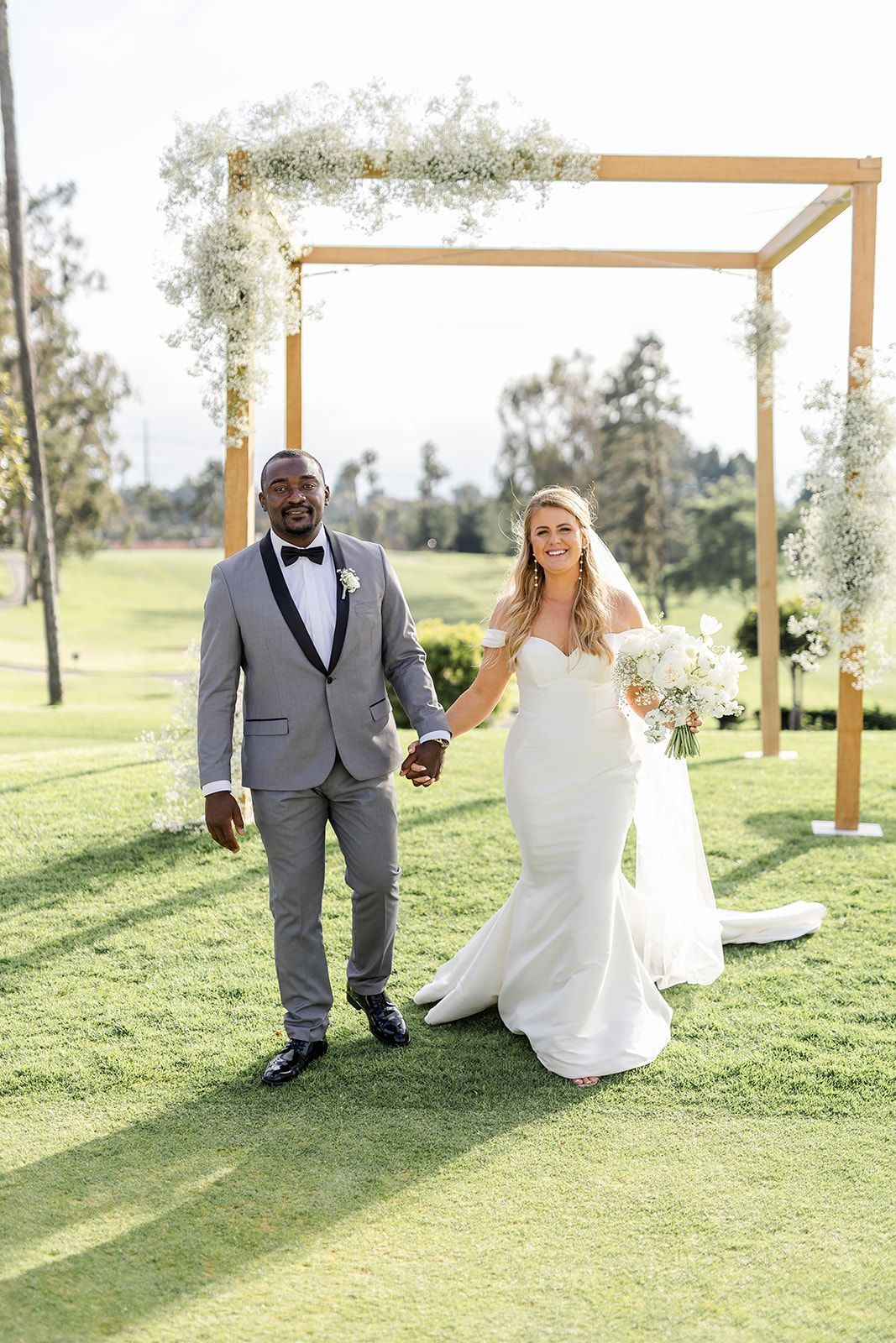 A bride and groom are holding hands while walking down the aisle at their wedding.