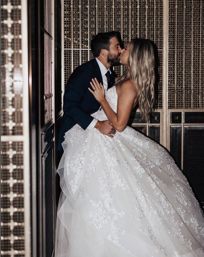 A bride and groom are kissing in an elevator.