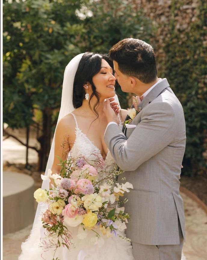 A bride and groom are kissing and the bride is holding a bouquet of flowers.