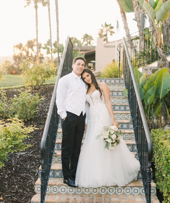 A bride and groom are posing for a picture on a set of stairs.