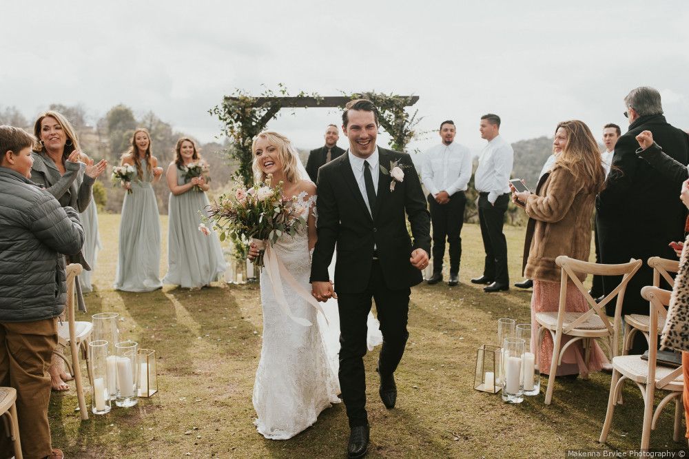 A bride and groom are walking down the aisle at their wedding holding hands.