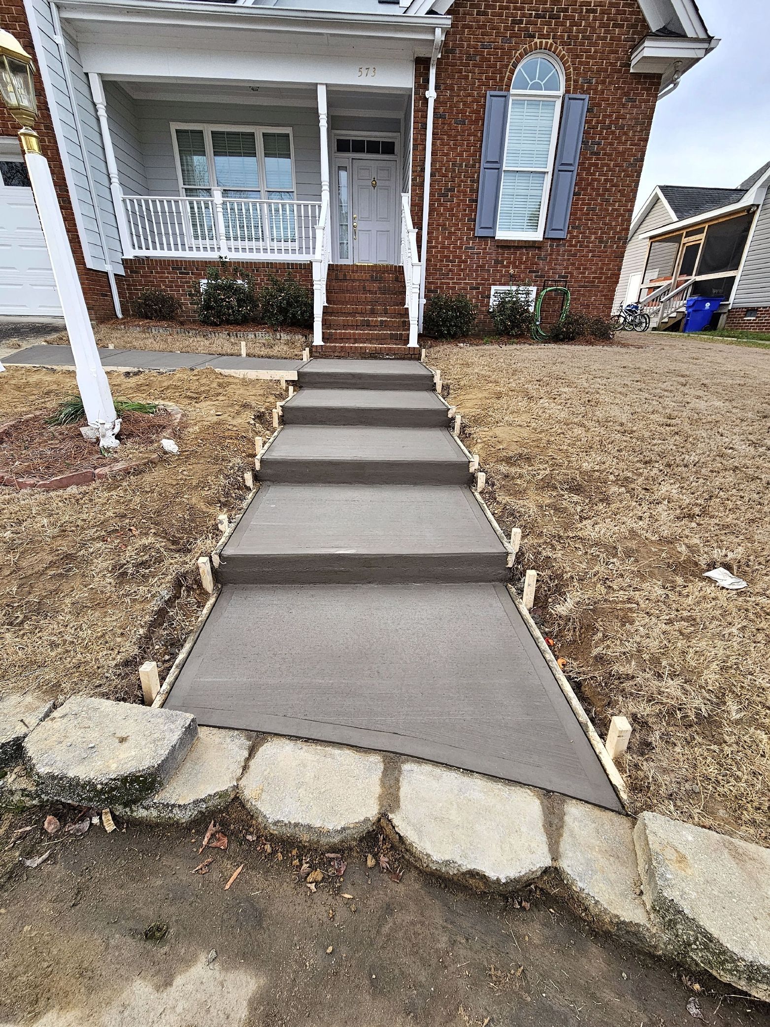 A concrete walkway leading up to a brick house.