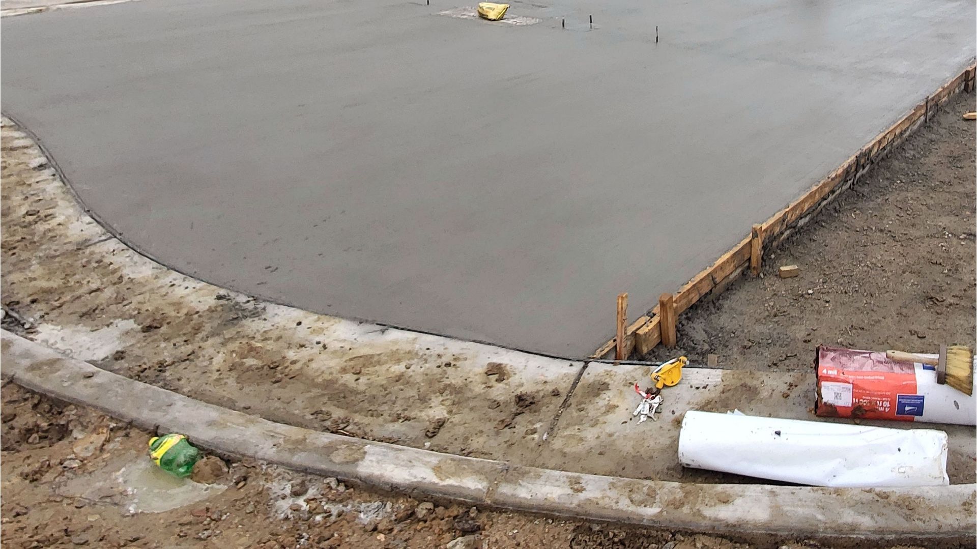 A concrete driveway is being built on a dirt road.