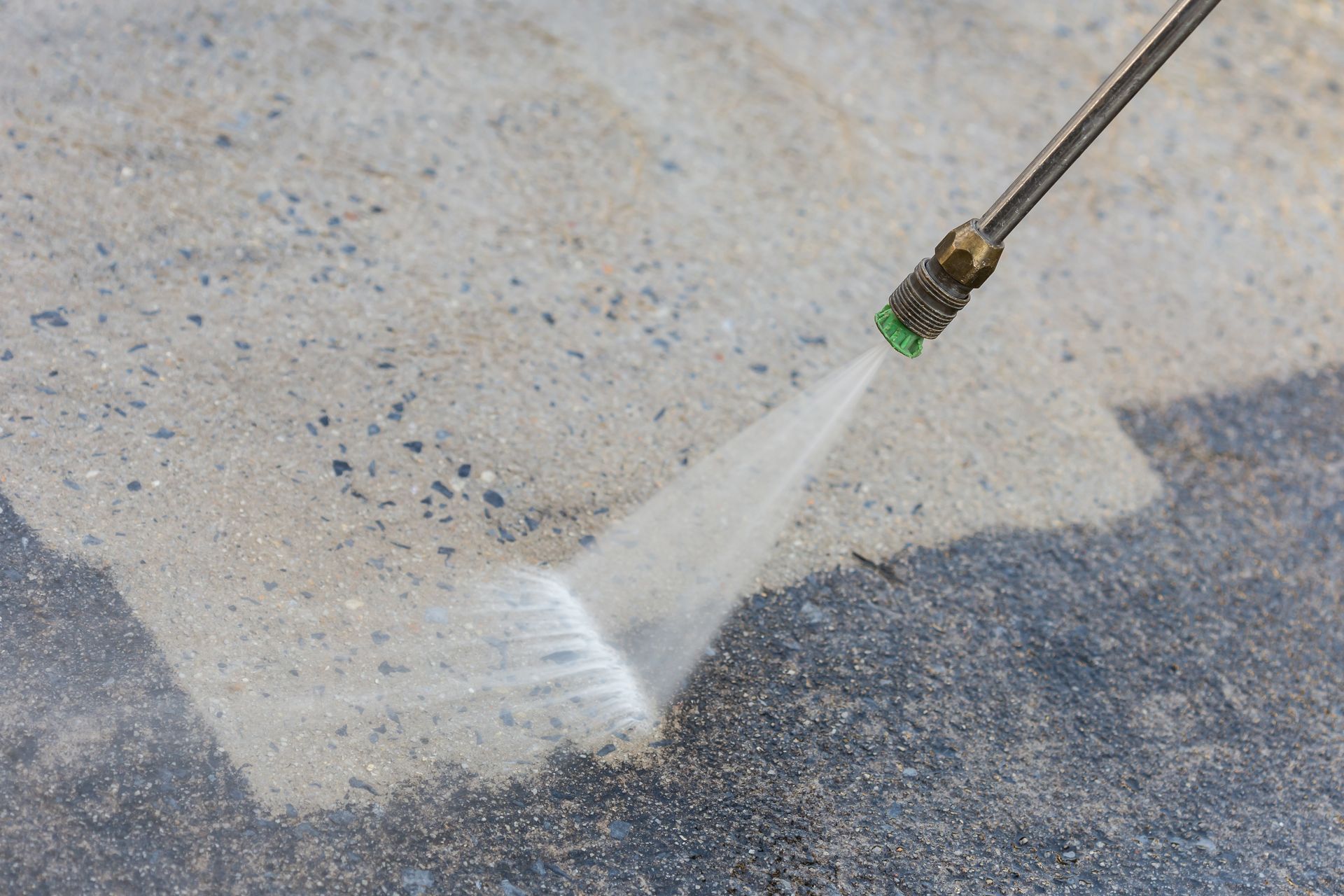 A person is using a high pressure washer to clean a concrete floor.