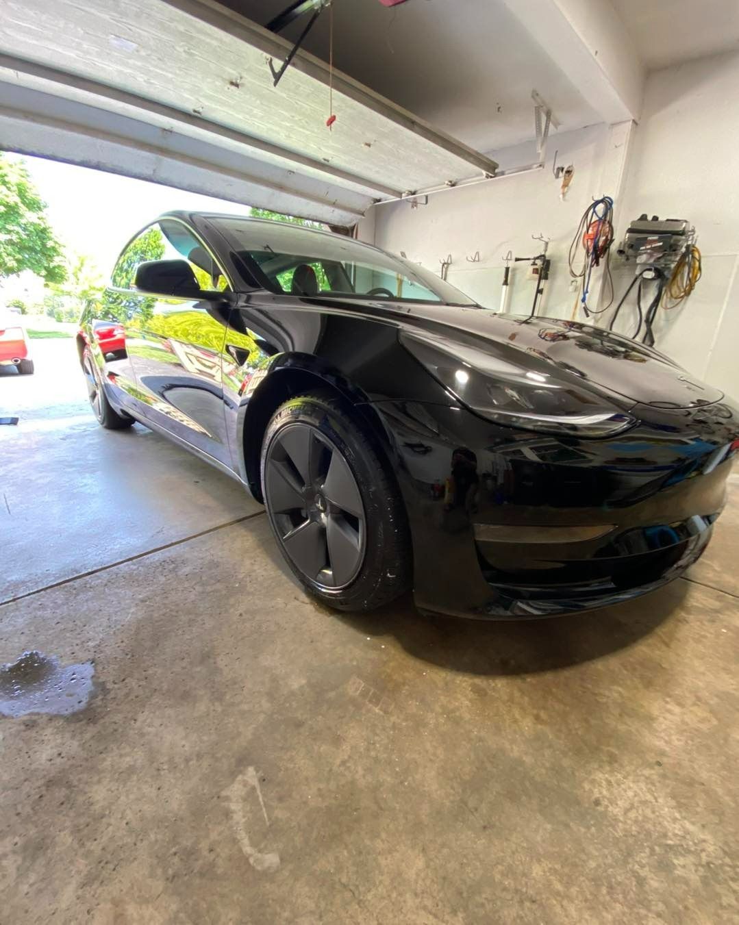 Black Tesla Model 3 parked in a garage.
