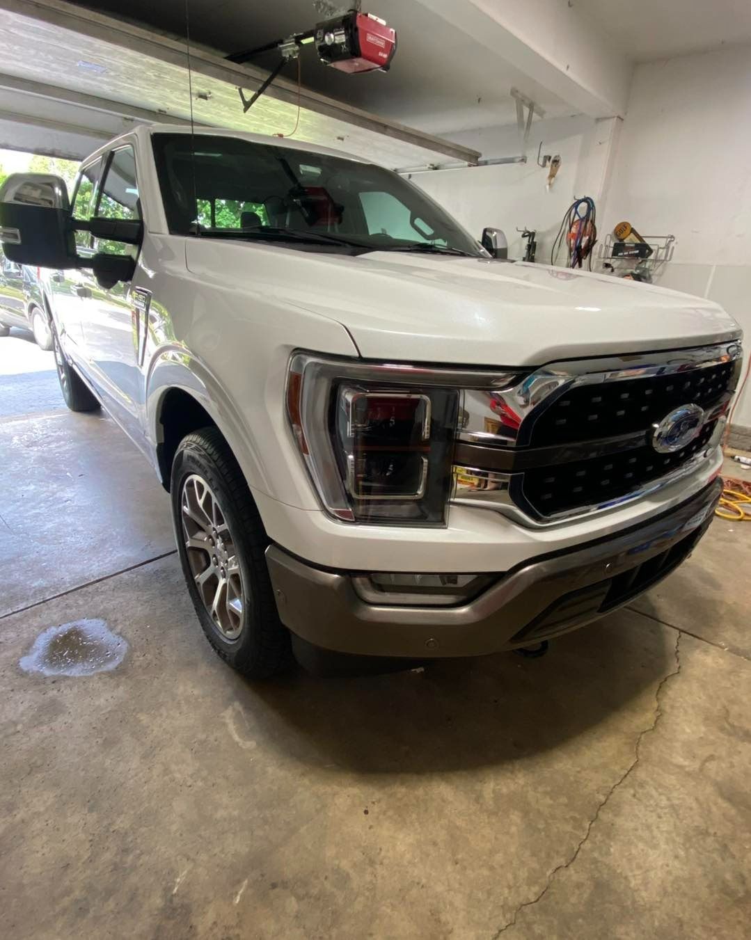 White Ford F-150 truck parked in a garage. Brown grill, chrome wheels, and large side mirrors.