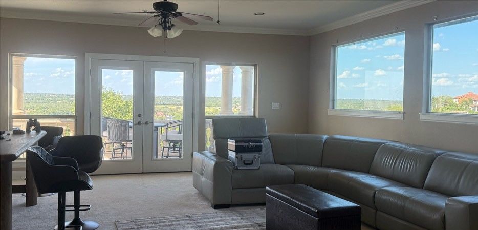 A bright living room with a large gray sectional sofa, a bar table with stools, and French doors leading to a balcony.