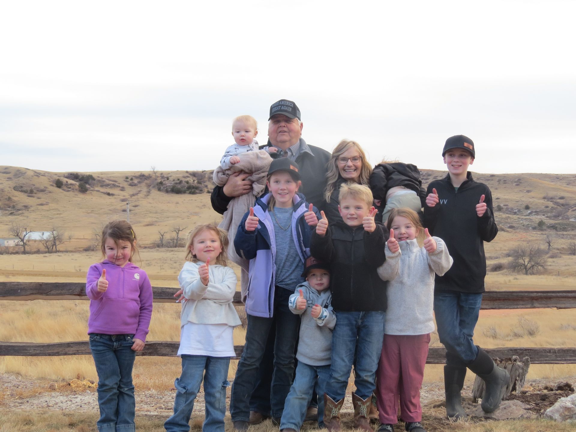 A group of children are sitting on a wooden fence.