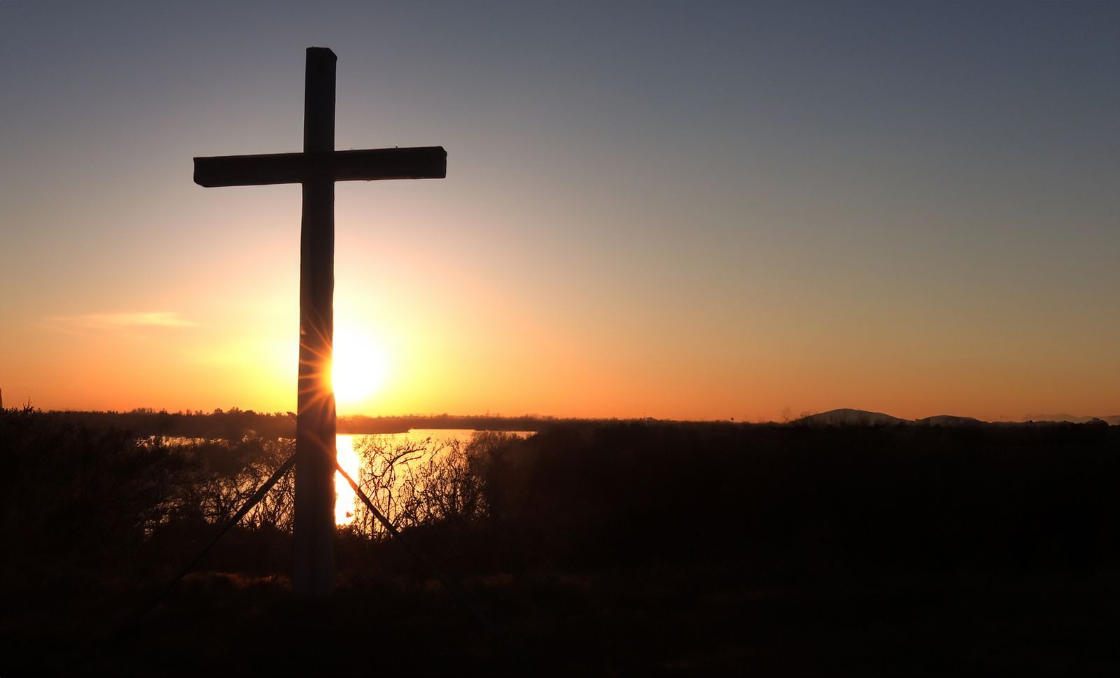 cross on a hill during sunrise