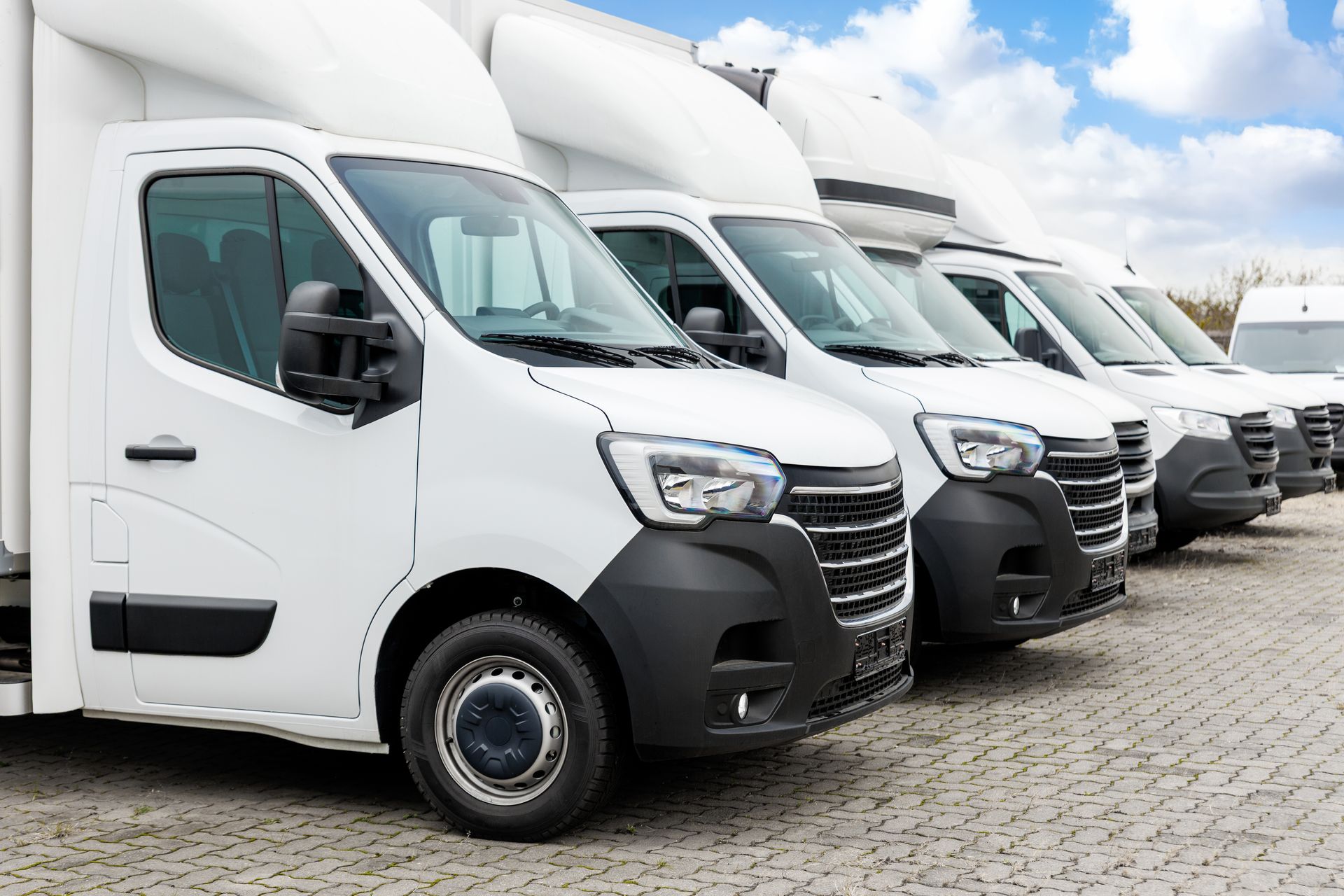 A fleet of modern white vans parked in a row outdoors, showcasing commercial auto insurance. A fleet of modern white vans parked in a row outdoors, showcasing commercial auto insurance.