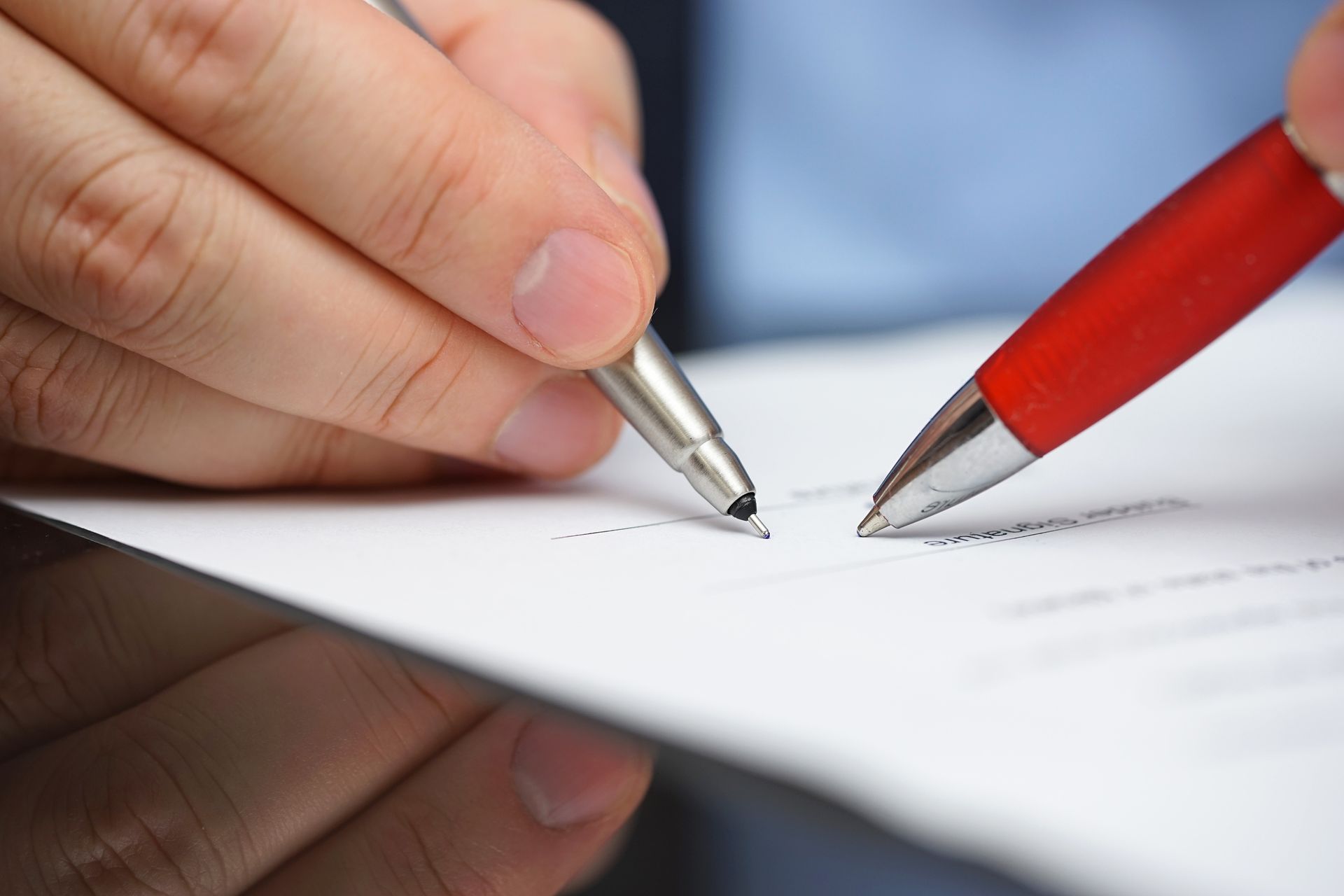 Close-up of hand holding a pen on top of a document, representing a business insurance agency.