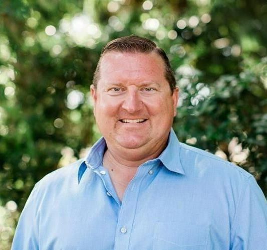 A man wearing a blue polo shirt is smiling for the camera.