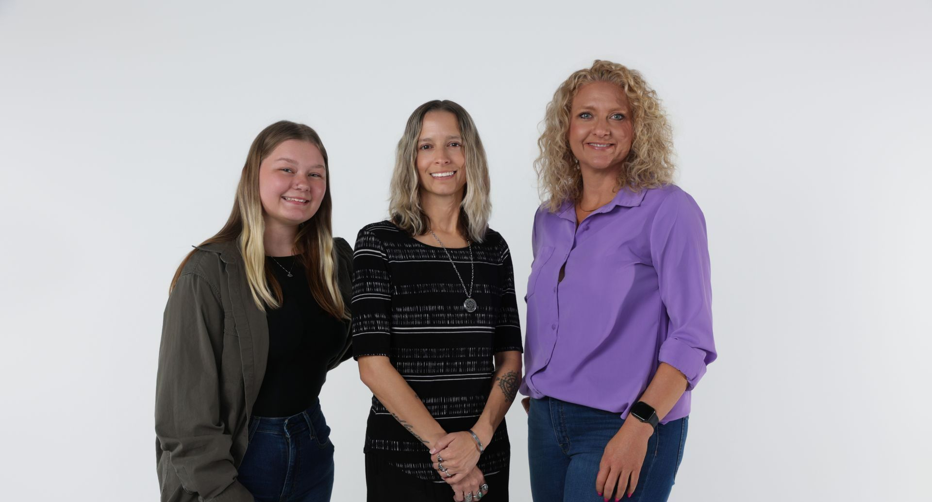 Three women are standing next to each other on a white background.