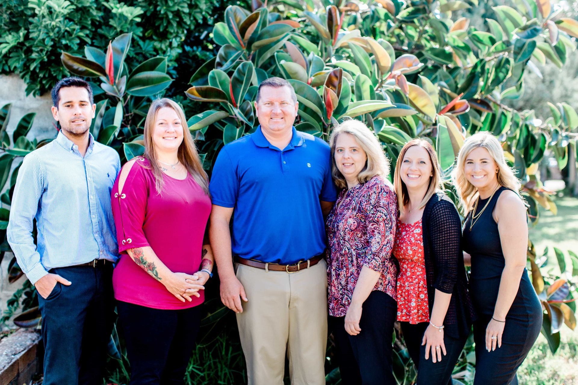 A group of people are posing for a picture in front of a tree.