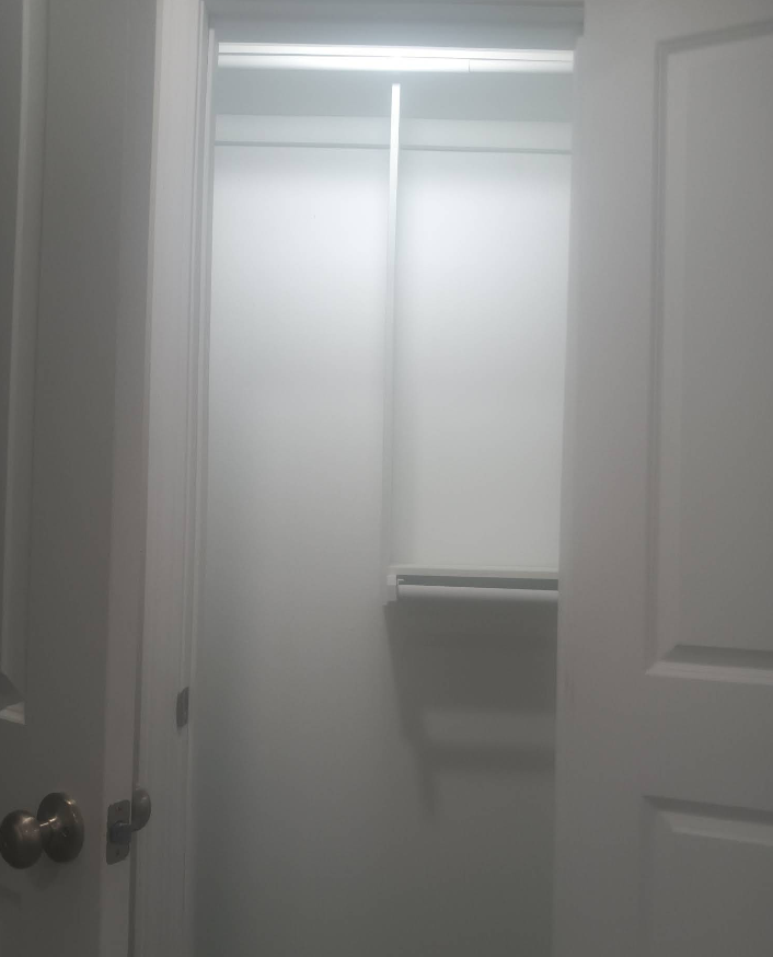 Empty, white closet with a shelf and hanging rod. Open door frame.