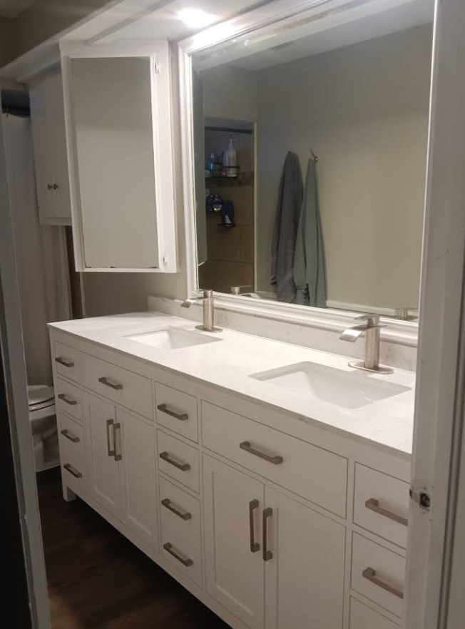 White double-sink vanity with silver hardware. Large mirror, two towels hanging in the reflection.