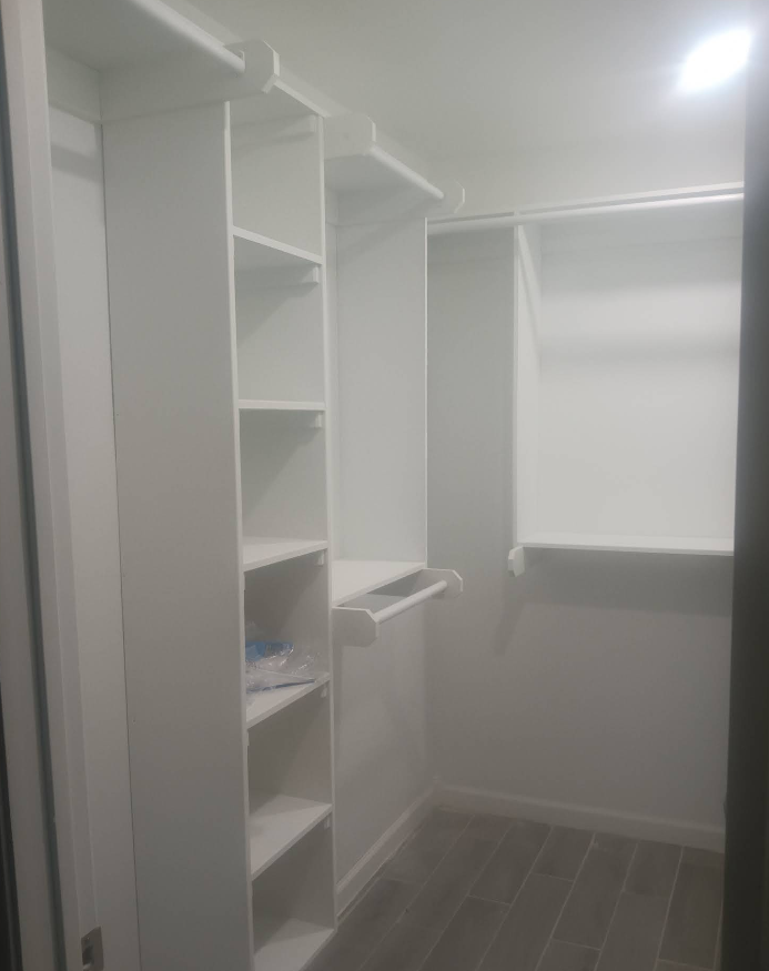 White closet with shelves and hanging rods; a minimalist, empty space.