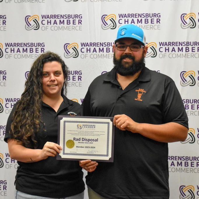 A man and a woman holding a certificate that says rad disposal