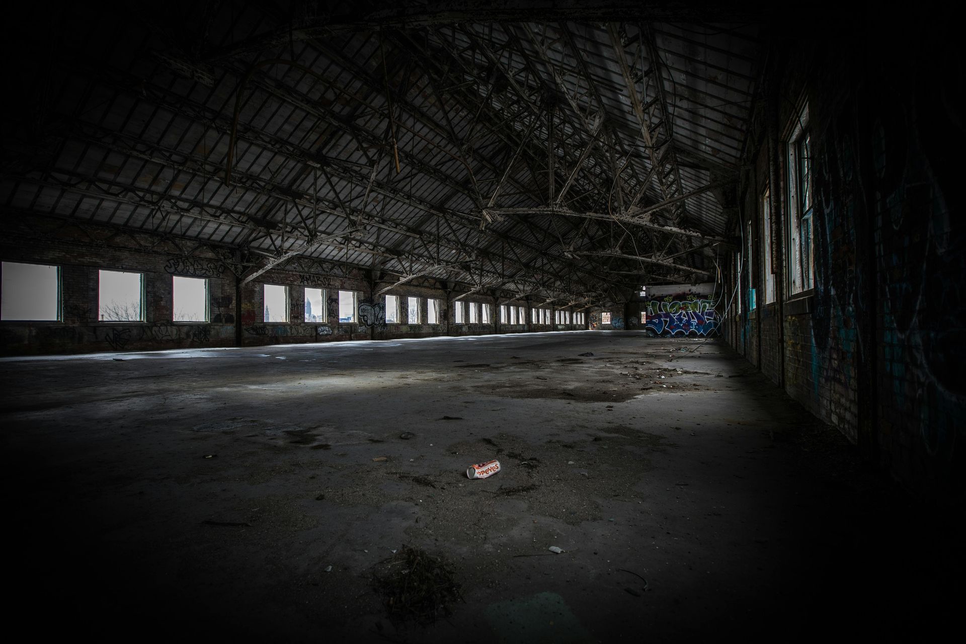 Interior of a large, decaying warehouse with rows of windows.