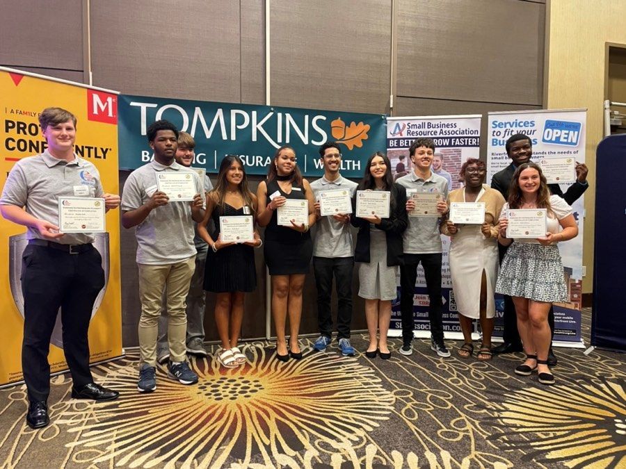 Group of people holding certificates, in front of a banner that reads 