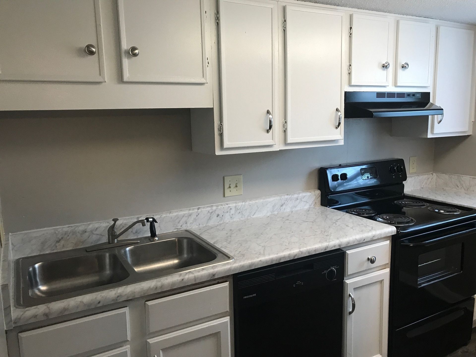 White kitchen cabinets, black appliances, and a stainless steel sink.